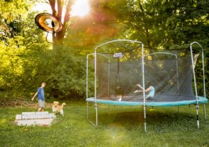 børn hopper på trampolin i haven, det er en havetrampolin og de har det sjovt. udeleg i haven giver sunde børn